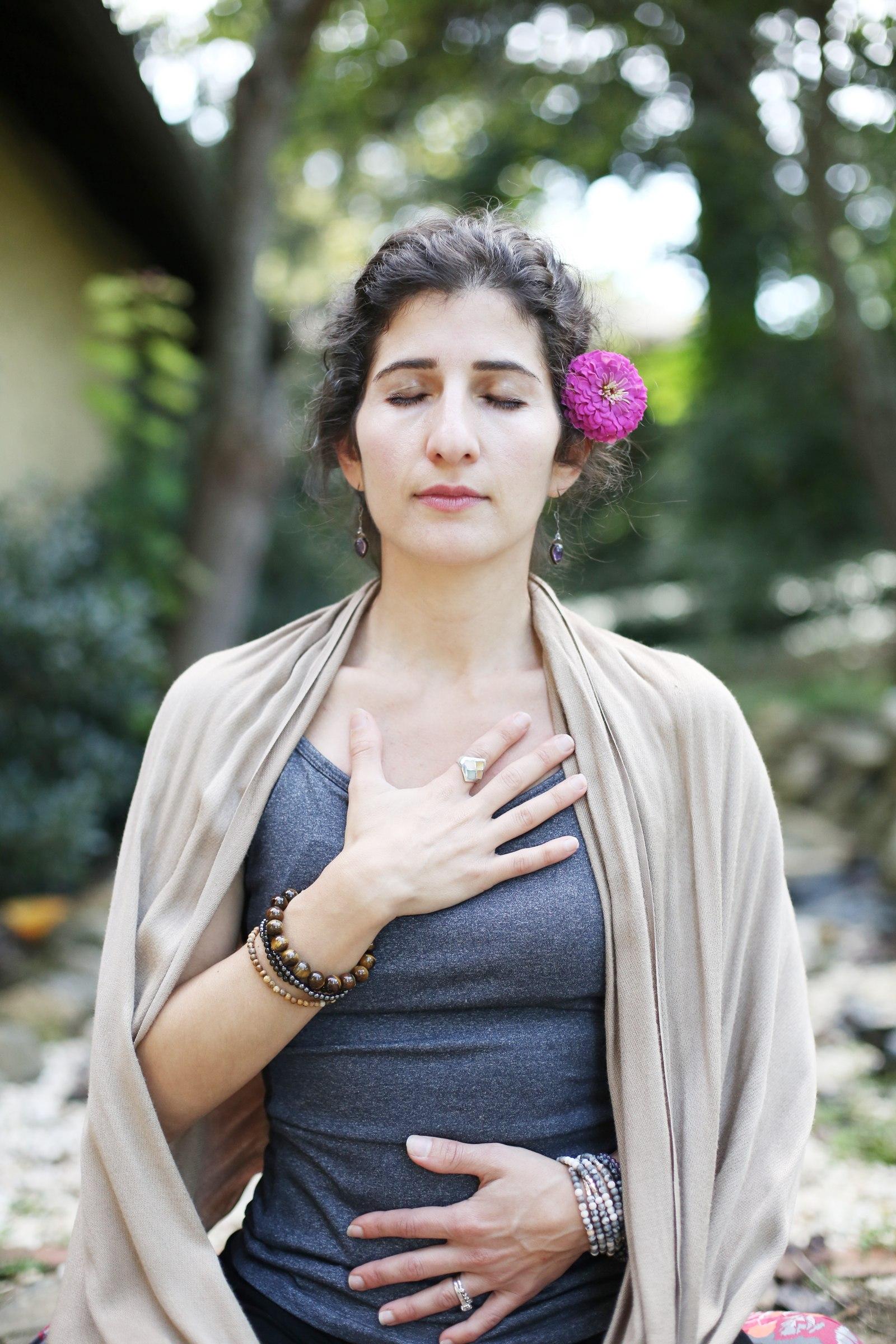 Maro with a flower in her hair, eyes closed, hand on heart
